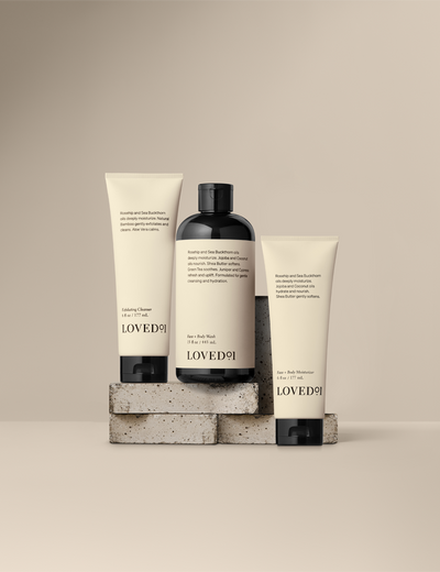 Product collection image with a tan background. The image shows the Exfoliating Cleanser, Face+Body Wash and  Face+Body Moisturizer,.