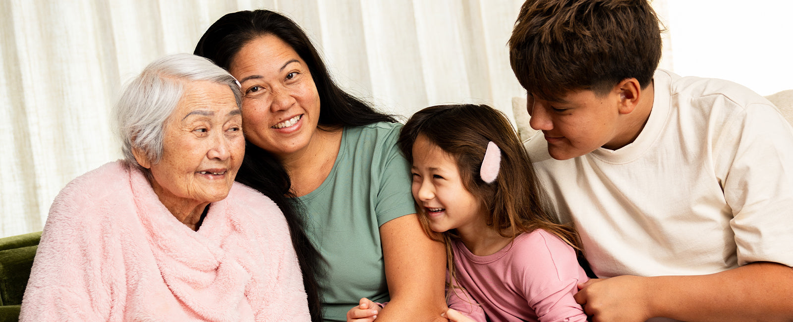 A multigenerational family, grandmother, adult daughter, and two grandchildren, laughing together at home