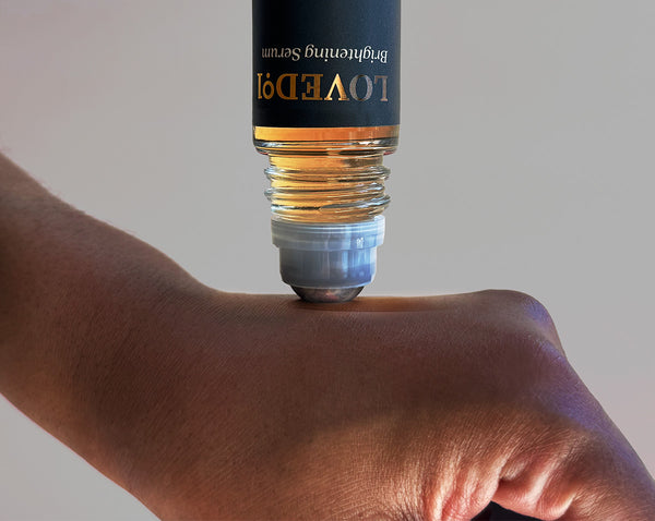 Close-up of a Loved01 rollerball applicator applying serum to a hand.