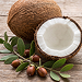 Two whole coconuts, one split open to show the white coconut flesh, on a dark background.