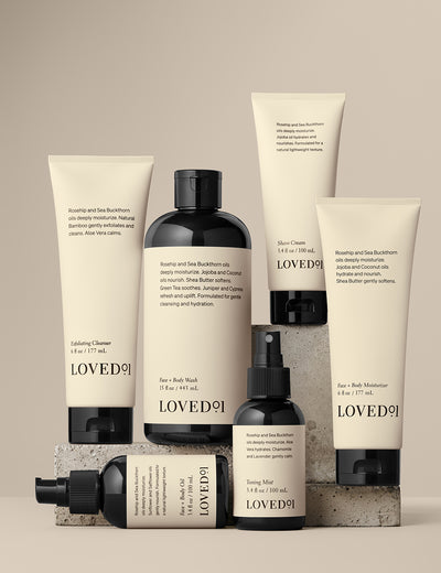 Product collection image with a tan background. The image shows the Exfoliating Cleanser, Face+Body Wash, Face+Body Oil, Toning Mist, Face+Body Moisturizer, and Shave Cream.