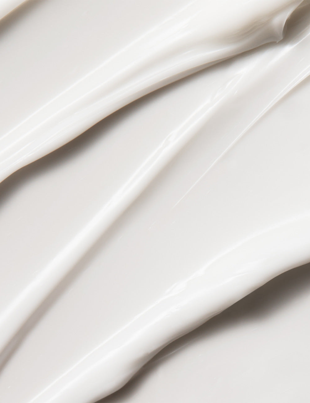 Close-up photo of a moisturizer being swirled or applied, with a creamy white texture, on a plain background.
